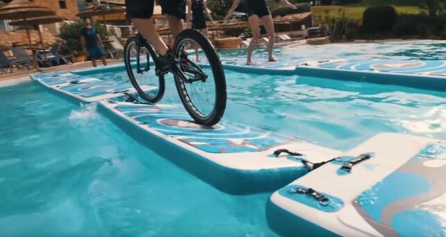 Aurélien Fontenoy traverse la piscine d'un hôtel en vélo sur des tapis Aquafitmat