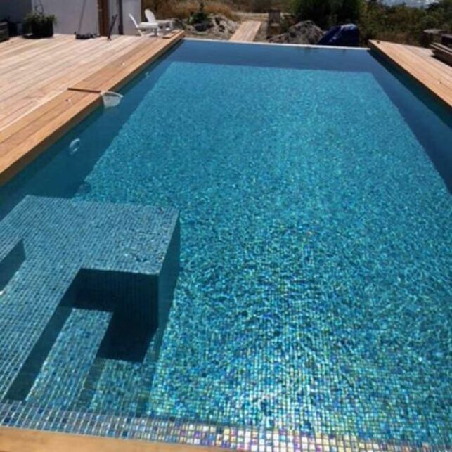 Une piscine avec revêtement mosaïque aux nuances de bleu et de vert pour une eau profonde