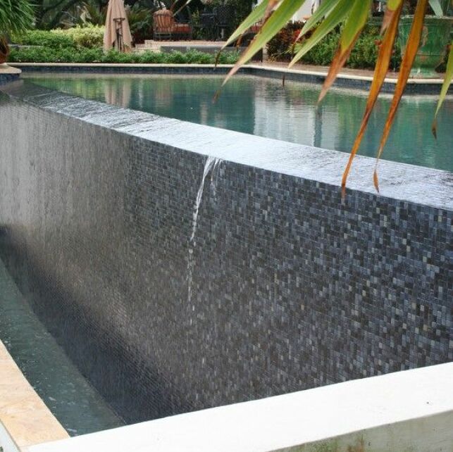Une piscine avec revêtement mosaïque sombre et en relief