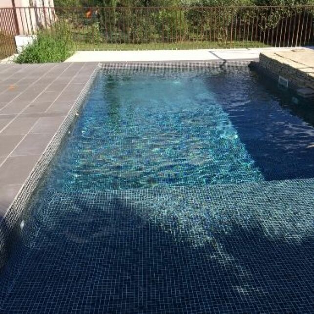 Une piscine avec revêtement mosaïque noire pour une eau façon miroir