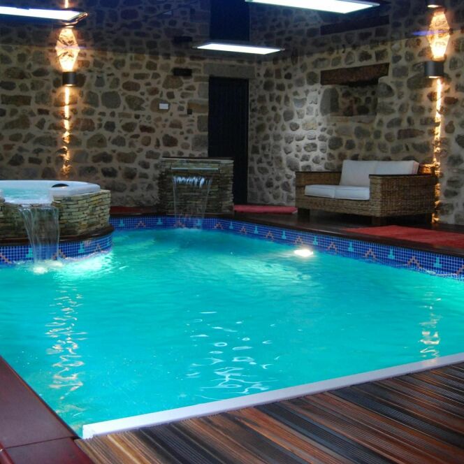 Piscine et spa installés dans un cadre sublime et chaleureux avec mur en pierre et sol en bois © L'Esprit piscine