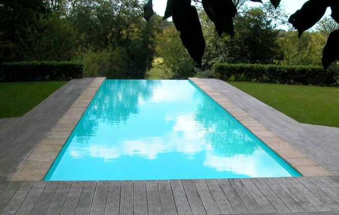 Piscine à débordement avec plage de bois et vue sur jardin aménagé © L'Esprit Piscine