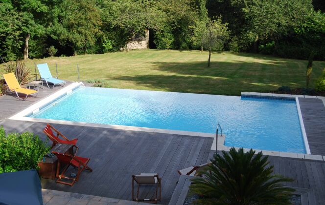 Piscine à débordement sur pelouse avec solarium en bois © L'Esprit Piscine