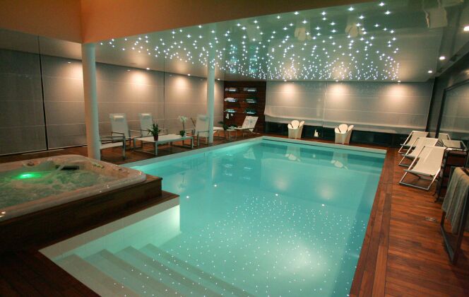 Piscine intérieure avec jacuzzi, plages de parquet en bois lustré et plafond étoilé de LED © L'Esprit Piscine