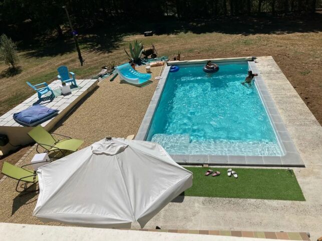 Cette piscine coque de 8 m par 4 est équipée d'un escalier avec un bain de soleil intégré.