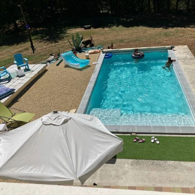 Cette piscine coque de 8 m par 4 est équipée d'un escalier avec un bain de soleil intégré.