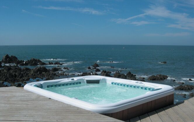 Spa extérieur avec solarium de bois et vue imprenable sur la mer. © L'Esprit Piscine