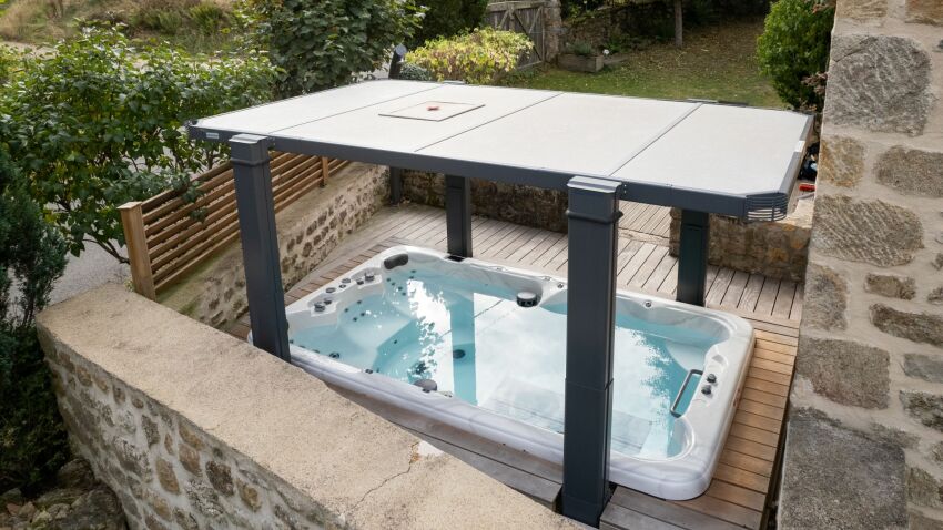 Spa de nage doté d'une couverture relevable, installé sur une terrasse en bois&nbsp;&nbsp;