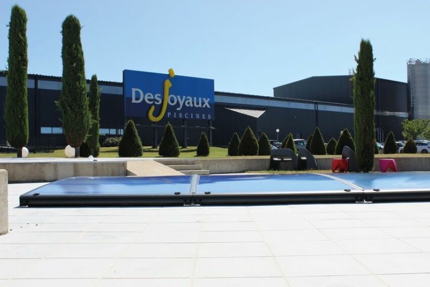 Une piscine recouverte d'un abri plat 4 éléments, située devant le siège de Piscines Desjoyaux 